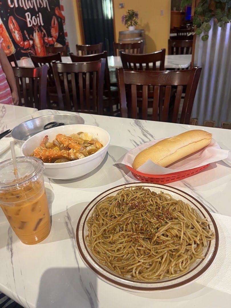 Garlic noodles beside crawfish in a bright restaurant setting.